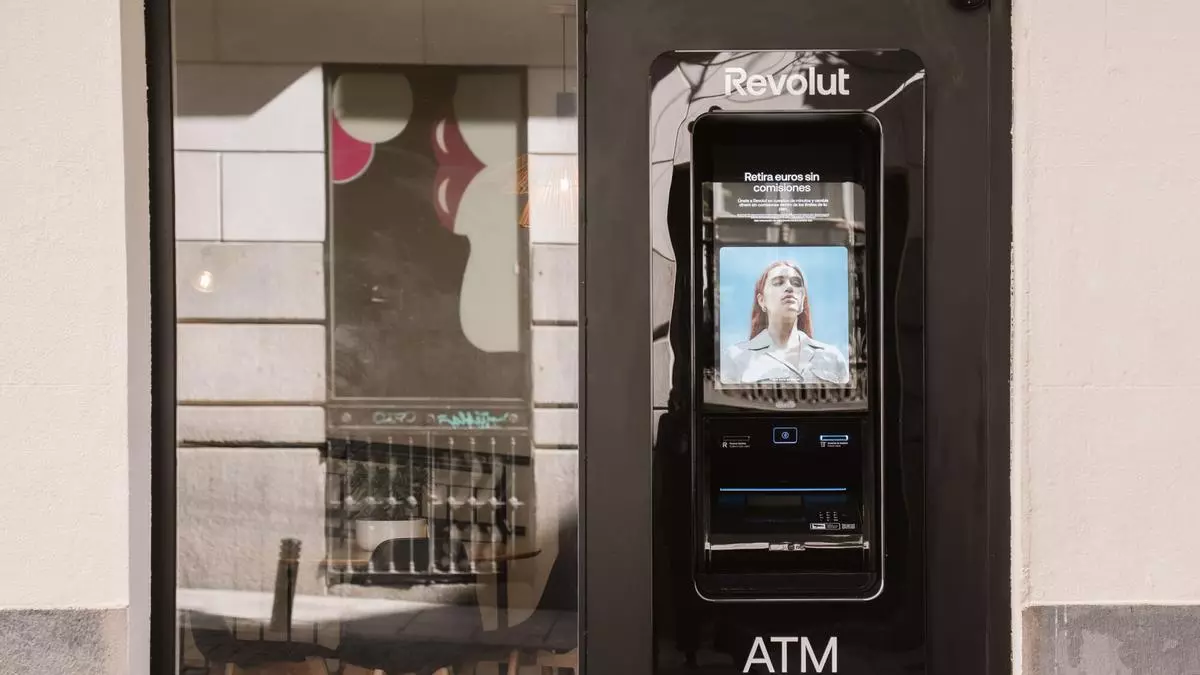 A pedestrian walks past a Revolut ATM installed in a Madrid storefront